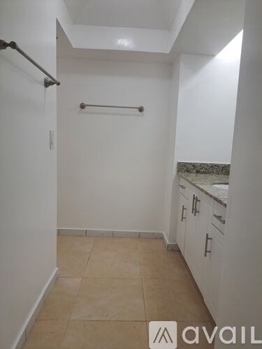 A white bathroom with a towel bar and a tiled floor.