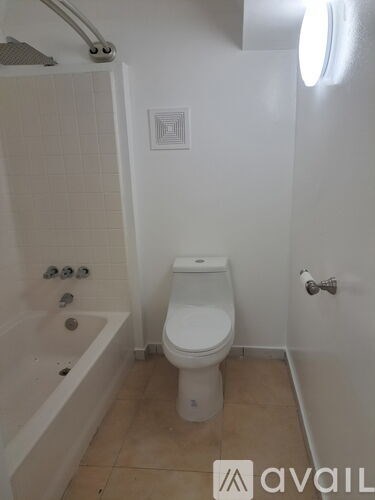 A white toilet in a small bathroom with a white tub and shower.