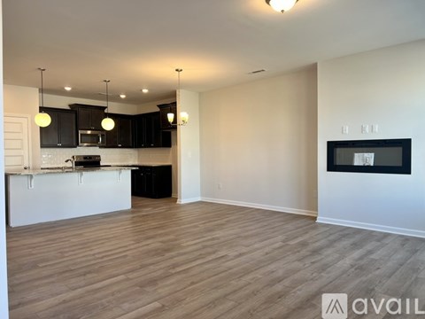 A spacious living room with wooden flooring and a television on the wall.