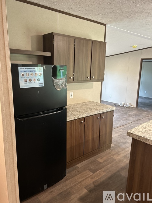 A black fridge in a kitchen with wooden cabinets.