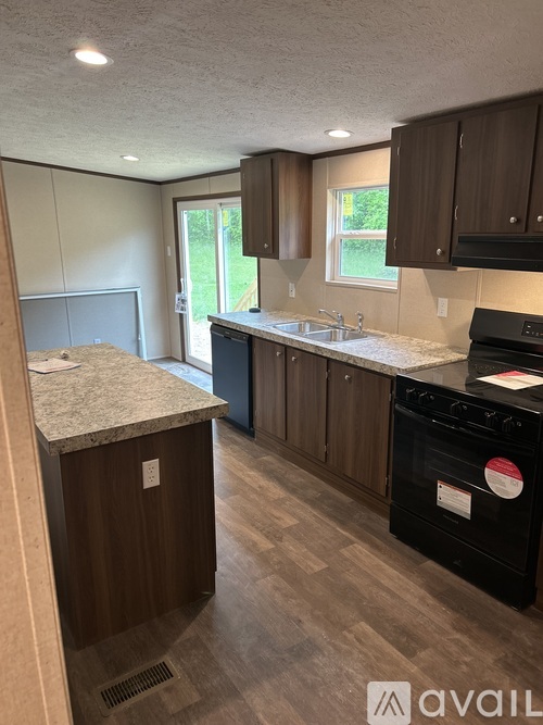 A kitchen with brown cabinets and a black dishwasher.