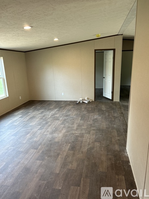 A room with wooden flooring and a doorway leading to another room.