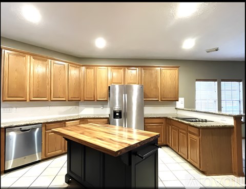 A kitchen with wooden cabinets and a stainless steel refrigerator.
