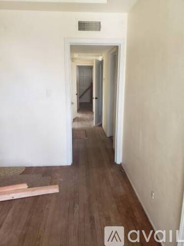 A long hallway with wood floors and white walls.