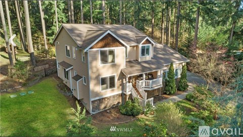 A house with a brown roof and a balcony is surrounded by greenery.