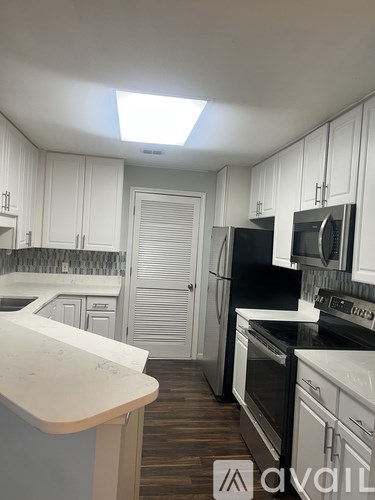 A kitchen with white cabinets and black appliances.