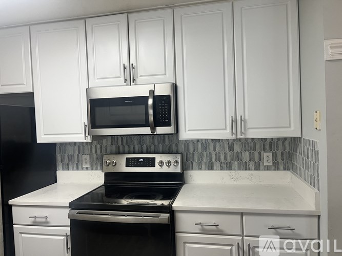 A kitchen with white cabinets and a black stove top oven.