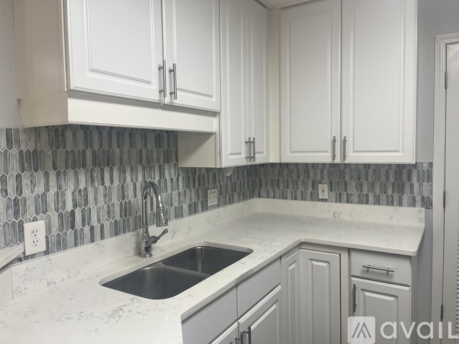 A kitchen with white cabinets and a marble countertop.