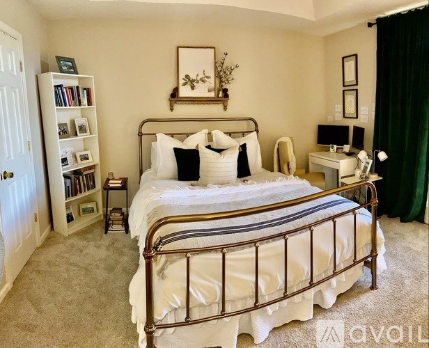 A bedroom with a large bed, a desk, and a bookshelf.