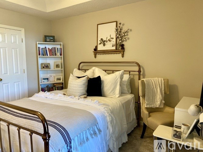 A bedroom with a bed, chair, and a bookshelf.