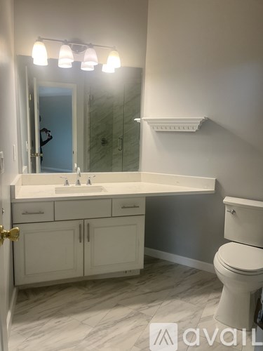 A bathroom with a white counter top and a white toilet.