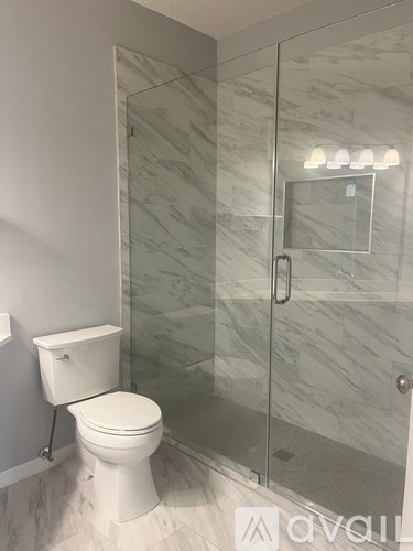 A white toilet sits next to a walk-in shower with a glass door.