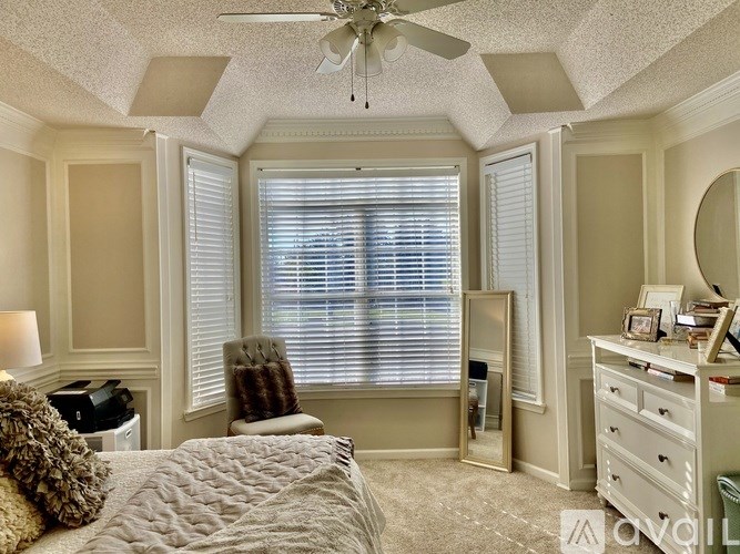 A bedroom with a bed, dresser, and window with blinds.