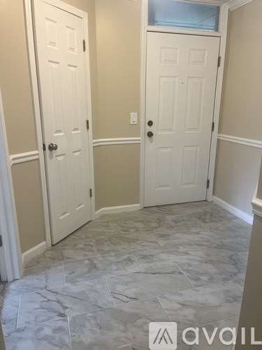 A hallway with two doors and a marble floor.