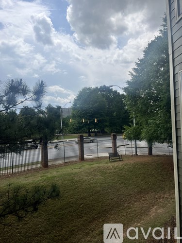 A view from a window of a fenced yard with trees and a street in the distance.