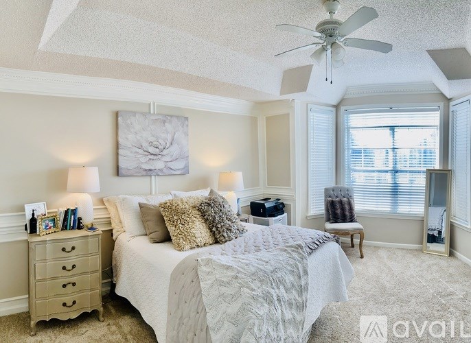 A bedroom with a large bed, a dresser, a chair, and a ceiling fan.