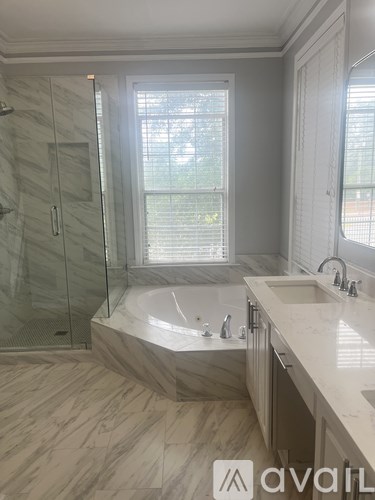 A bathroom with a marble floor and a glass shower stall.