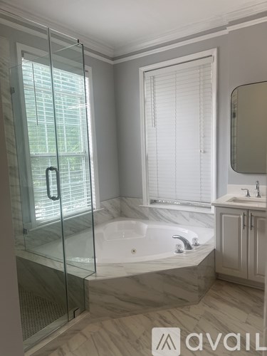 A bathroom with a glass shower door and a bathtub.