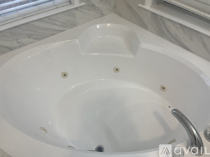 A white bathtub with a silver faucet and four holes in the center.