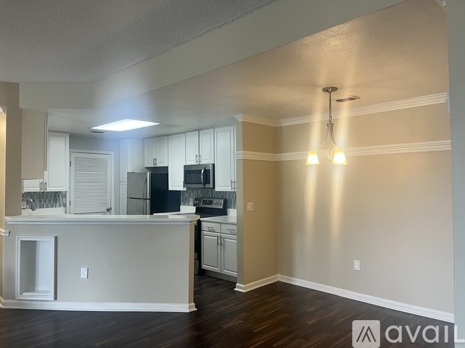 A kitchen with white cabinets and a wooden floor.