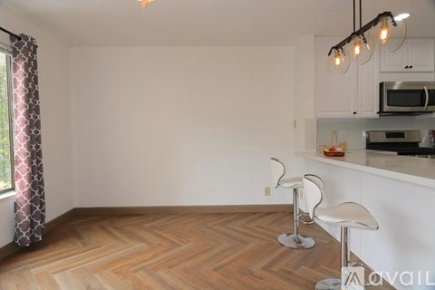 A kitchen with a bar stool and a countertop with a microwave and oven.
