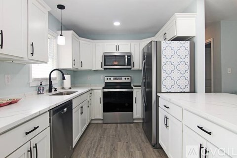 A kitchen with white cabinets and a black fridge.
