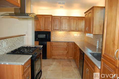 A kitchen with wooden cabinets and a black stove top.