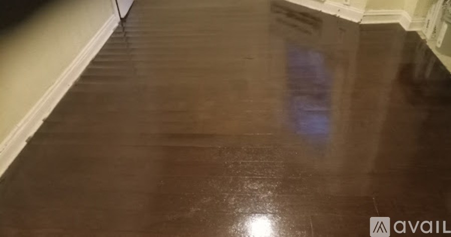 A dark brown wooden floor with a reflection of a light source.