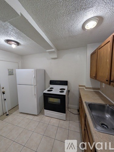 A kitchen with a white refrigerator, black stove, and a sink.