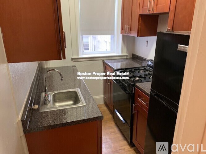 A kitchen with brown cabinets and a black refrigerator.