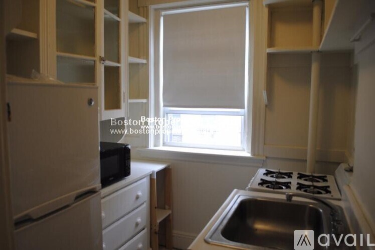 A kitchen with a stove, sink, and cabinets.