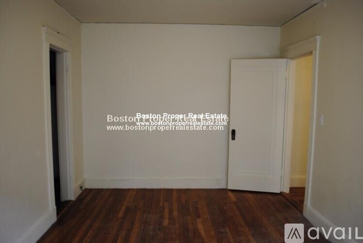 A room with wooden floors and two doors, one of which is open.