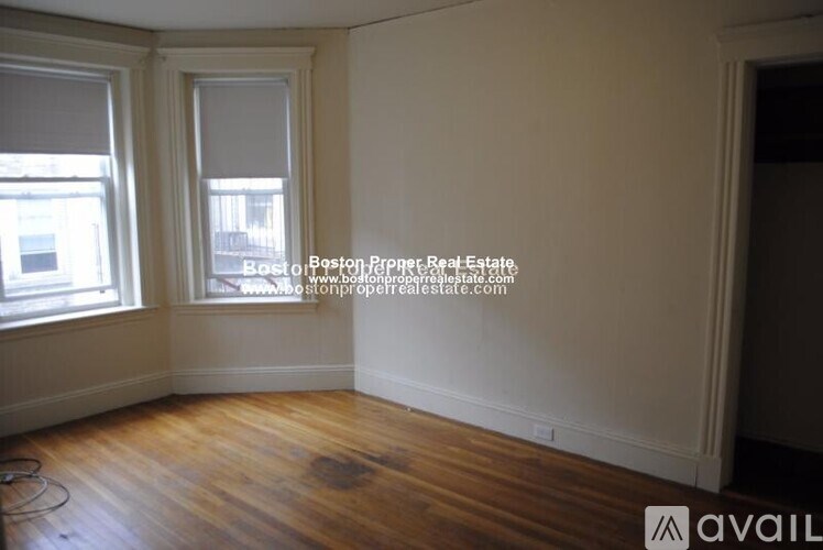 A room with wooden floors and two windows.