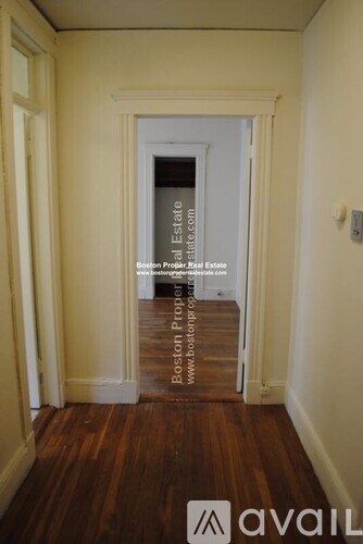 A hallway with a door at the end and a sign on the floor.