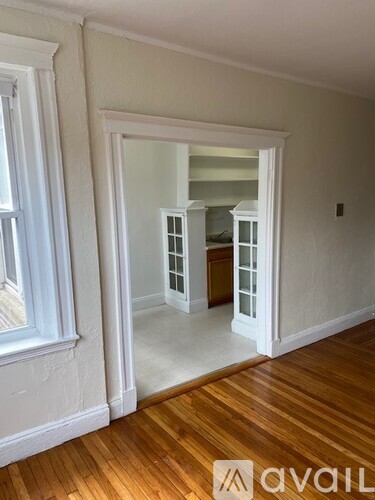 A room with a wooden floor and a white cabinet with glass doors.