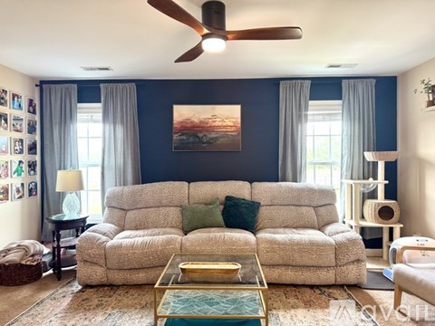 A living room with a large couch and a ceiling fan.