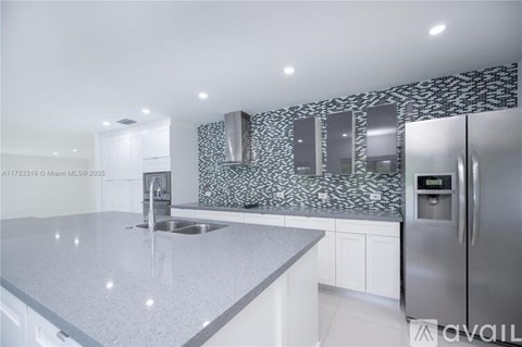 A modern kitchen with a stainless steel refrigerator and a granite countertop.
