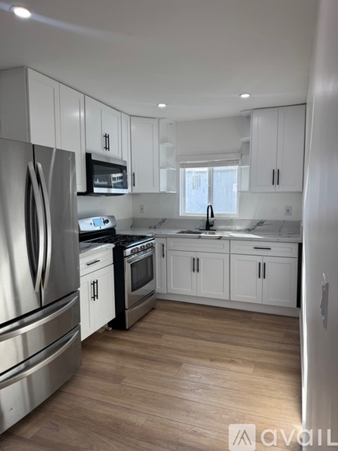 A modern kitchen with white cabinets and stainless steel appliances.