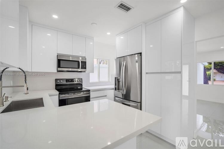 A modern kitchen with white cabinets and stainless steel appliances.