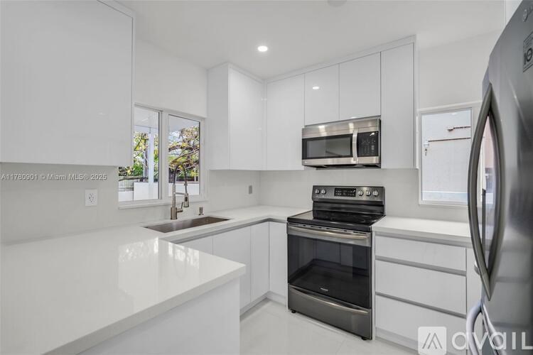 A modern kitchen with white cabinets and stainless steel appliances.