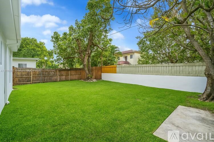A backyard with a white fence and a tree.