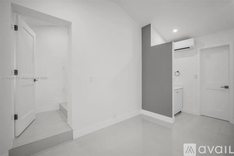 A spacious room with white walls and a white door.