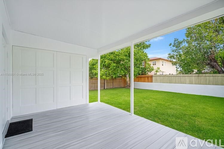A room with a white door and a window with a view of a backyard.