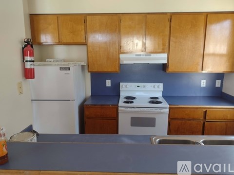 A kitchen with a white refrigerator, white stove, and wooden cabinets.