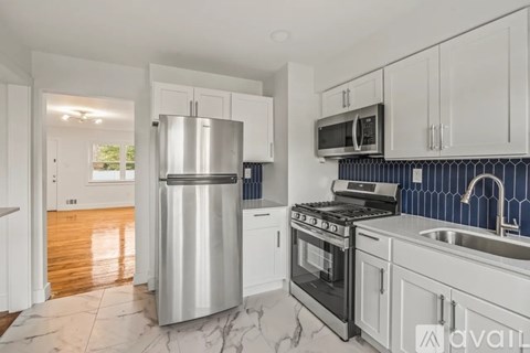 A modern kitchen with a stainless steel refrigerator and a black and white tiled backsplash.