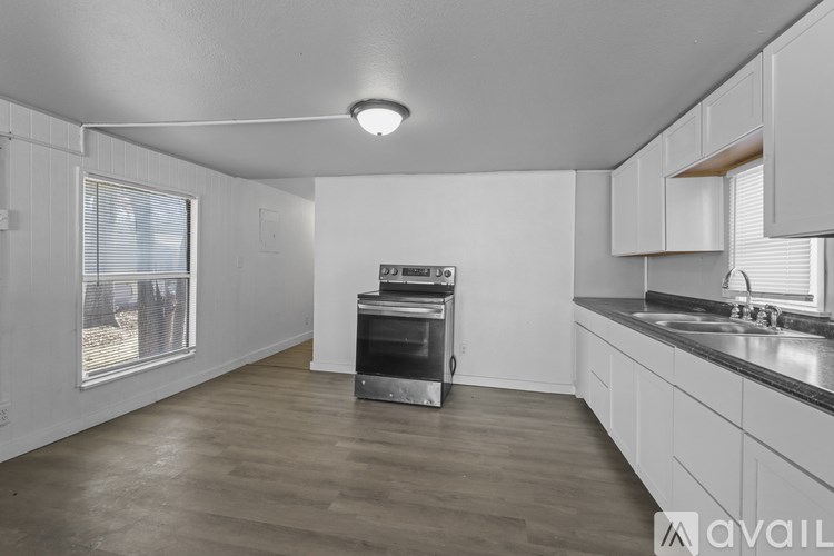 A kitchen with white cabinets and a wooden floor.