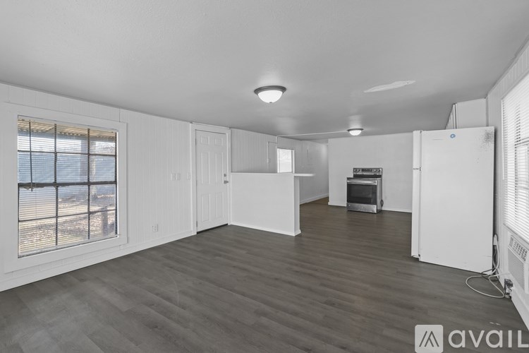 A spacious, empty room with wooden flooring and white walls.