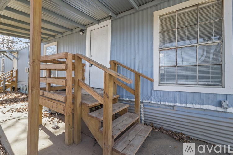 A wooden staircase leads to a door on the porch of a house.