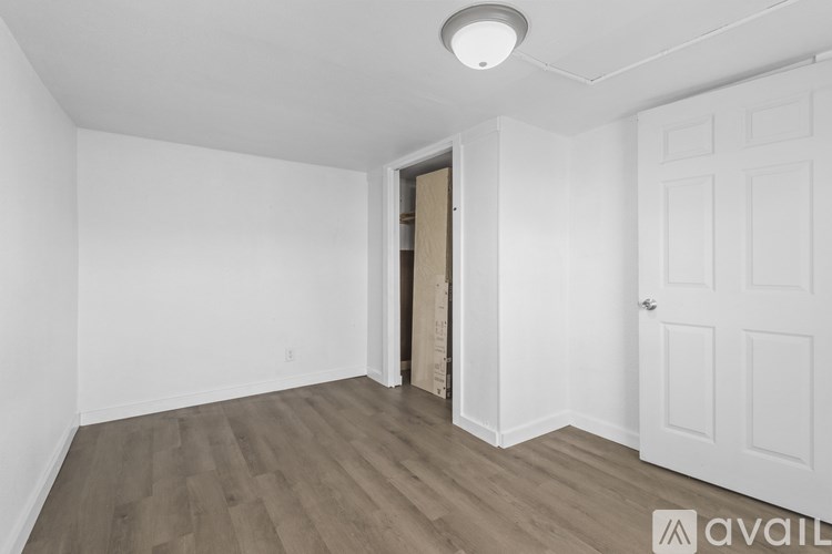 A room with a white door and a wooden floor.