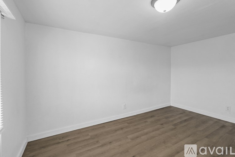 A room with wooden flooring and white walls.